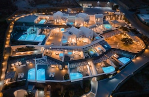 Luchtbeeld van een resort met meerdere zwembaden, onderling verbonden gebouwen en buitenterrassen.
