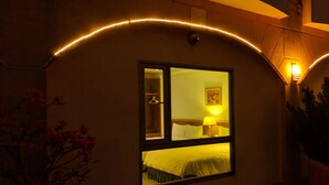 Ein Hotelzimmer mit großem Fenster, einem Bett, einem Nachttisch und einer Lampe.