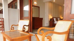 A wooden table and two wicker chairs in a room with a wooden cabinet and a mirror on the wall. - Paradise Beach Club (Mirissa)