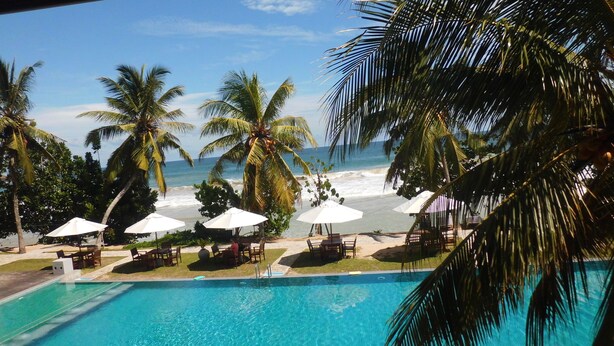 A poolside view with a clear view of the ocean, palm trees, and beach umbrellas. - Paradise Beach Club (Mirissa)