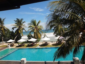 A poolside view with a clear view of the ocean, palm trees, and beach umbrellas. - Paradise Beach Club (Mirissa)