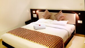 Une chambre d’hôtel équipée d’un lit, d’un ventilateur de plafond, d’un éclairage encastré, d’un climatiseur et d’une table de chevet.