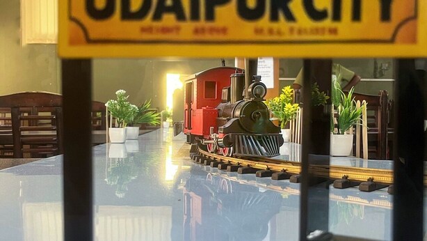 Un train miniature circule sur une voie ferrée, et un panneau indique : « UDAIPUR CITY ».