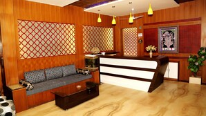 Un espace d’accueil comprenant un comptoir de réception en bois, un canapé agrémenté de coussins à motifs et un aquarium décoratif.