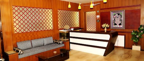 A reception area with a wooden reception desk, a sofa with patterned cushions, and a decorative fish tank.