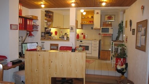 A compact kitchen with wooden cabinets, a microwave, and a sink. - Pension Sonne Bed & Breakfast (Bregenz)