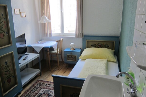 A bedroom with a bed, desk, chair, and a small table. - Pension Sonne Bed & Breakfast (Bregenz)