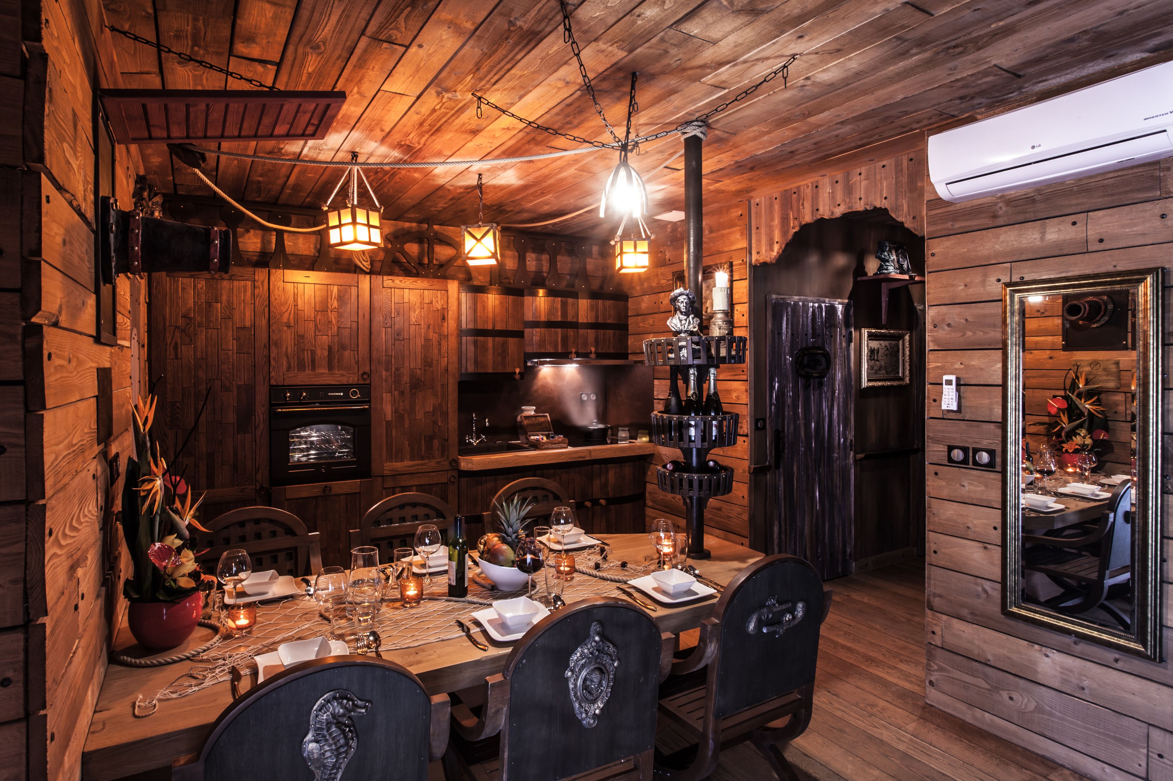 Un intérieur rustique en bois, avec une table à manger dressée pour quatre personnes, entourée de chaises.