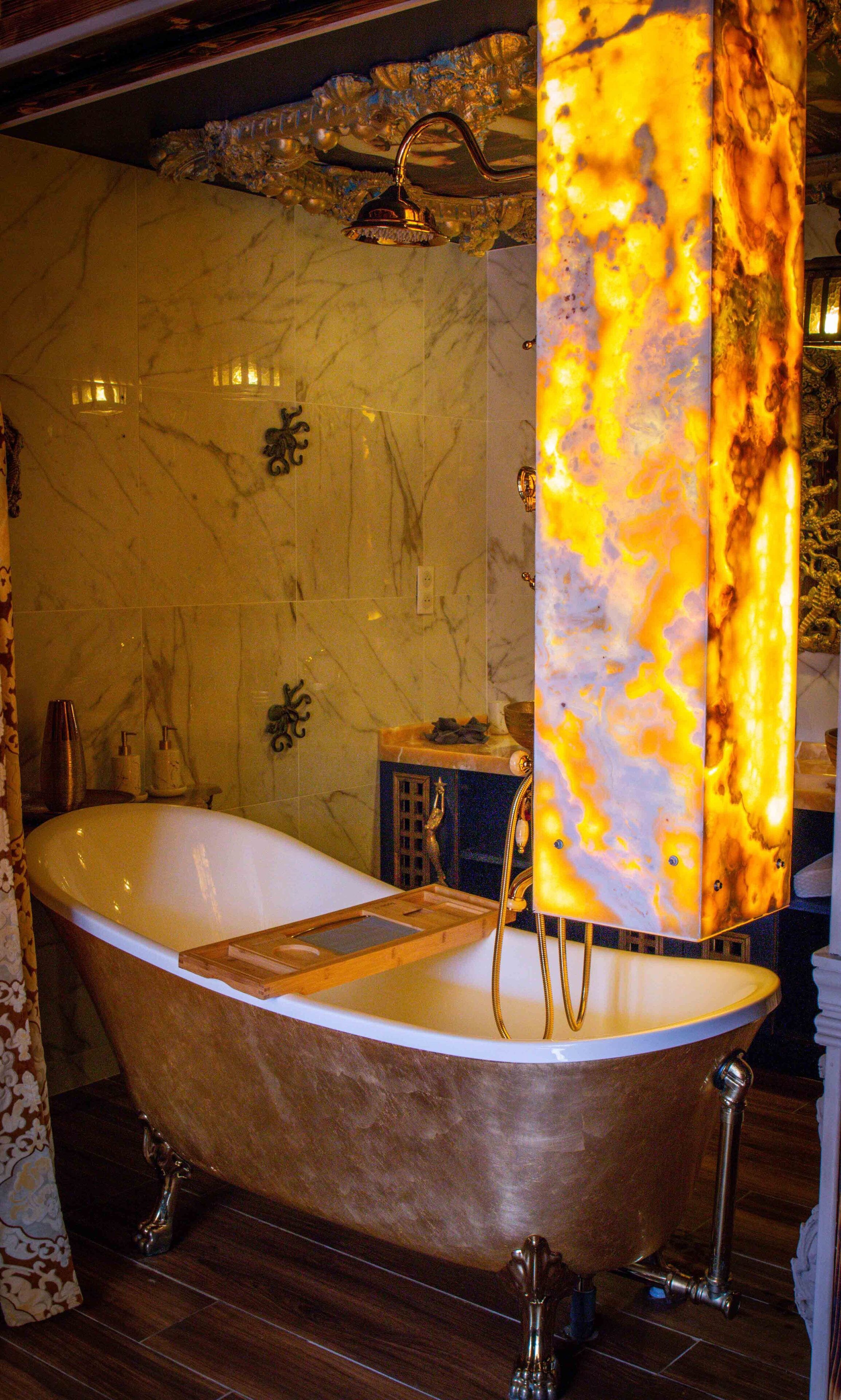 A classic clawfoot bathtub in a luxurious bathroom with marble walls and ornate fixtures.