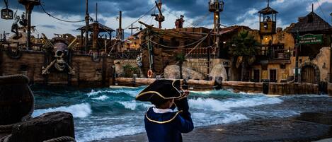 A pirate-themed attraction with a wooden ship structure, a skull, and a person in a pirate costume.