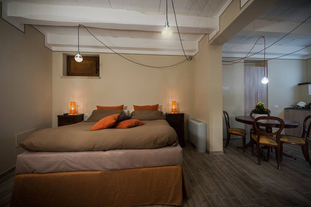 Een slaapkamer met een groot bed, nachtkastjes en een zithoek met stoelen en een tafel.