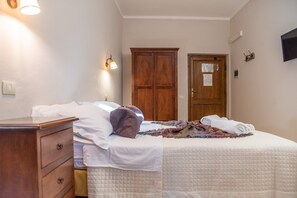 Un dormitorio con cama, cómoda, armario de madera y una puerta con un aviso.