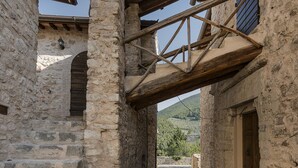 A narrow stone pathway leading to a rustic building with wooden beams and stone walls.