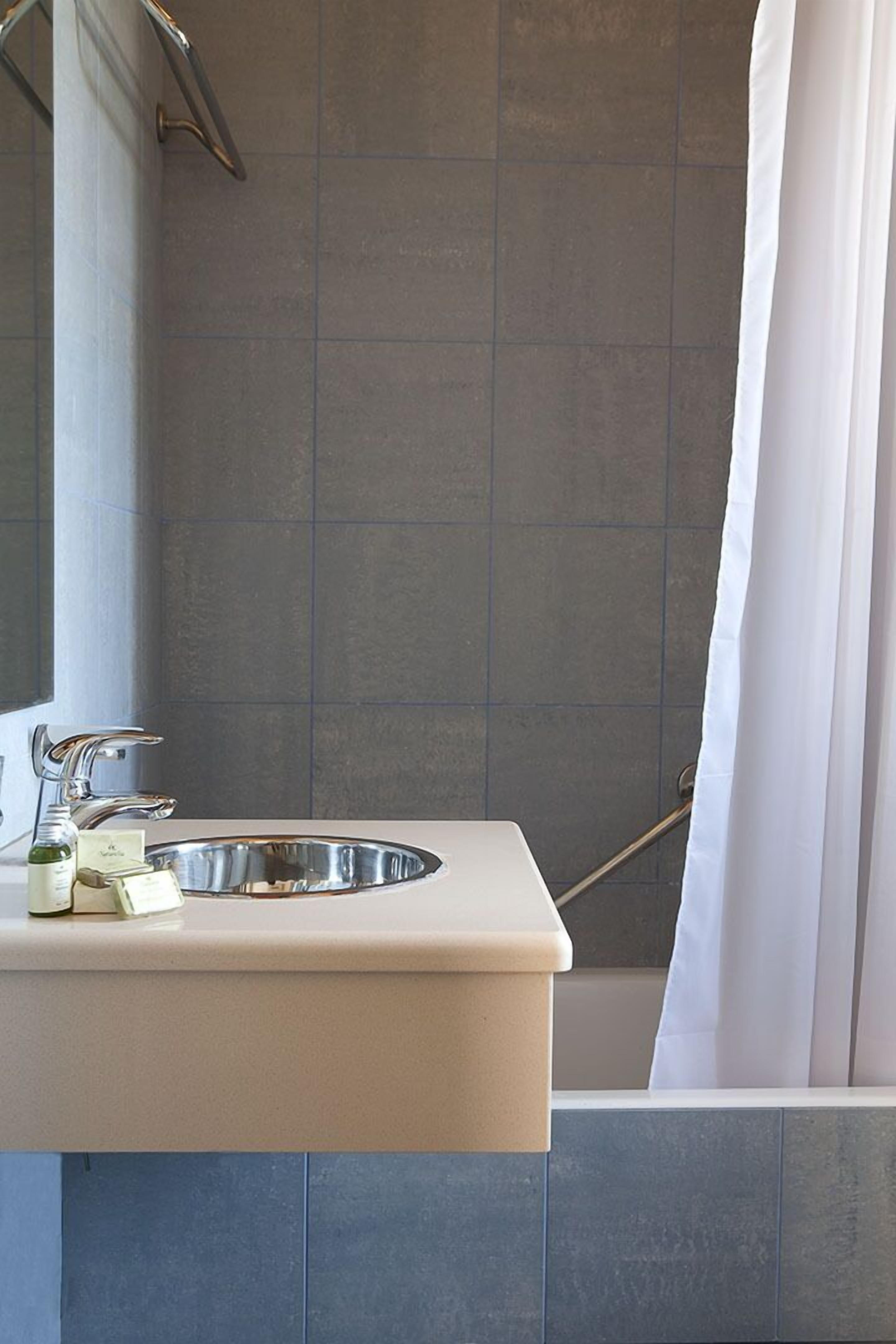 A bathroom with a sink, mirror, and shower curtain.