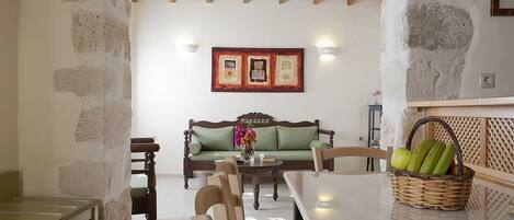 A dining area with a table, chairs, a sofa, and a wall-mounted picture.