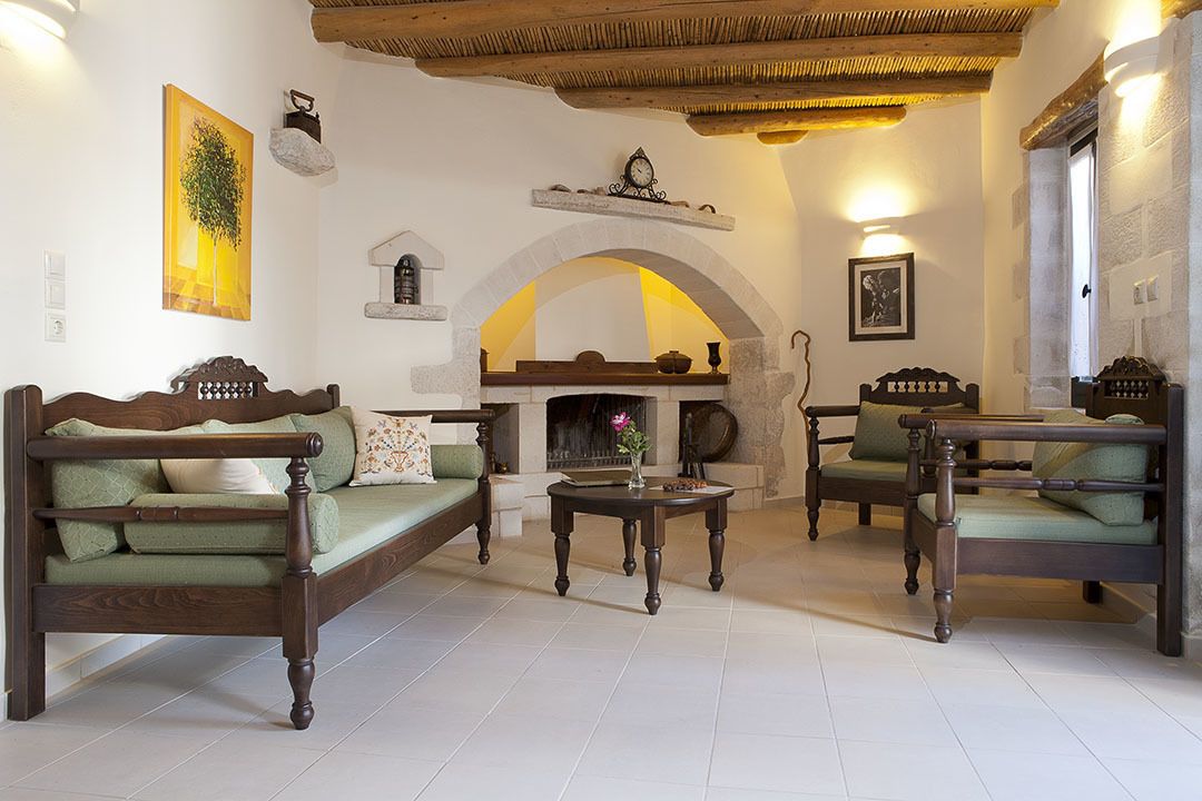 A cozy living room with two wooden sofas, a round coffee table, and a fireplace.