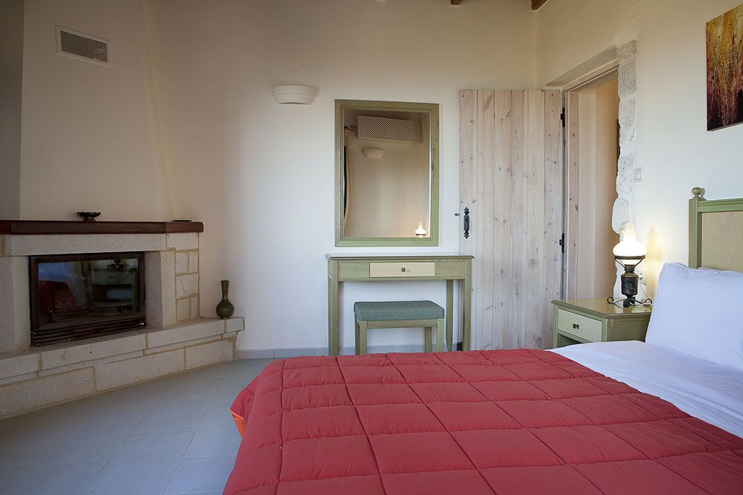 Un dormitorio con cama, cómoda, espejo, mesita de noche y chimenea.