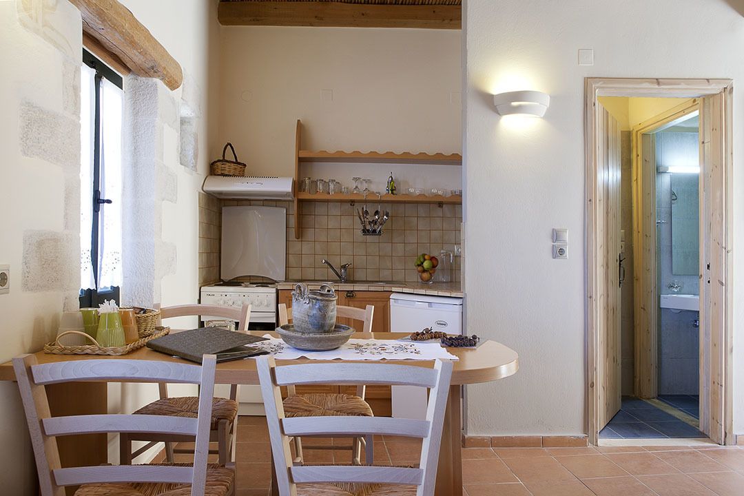 A dining area with a table, chairs, and a kitchen in the background.