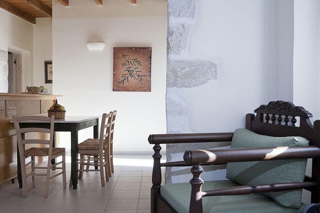 Ein Zimmer mit einem hölzernen Bett, einem Esstisch mit Stühlen und einem an der Wand befestigten Kunstwerk.