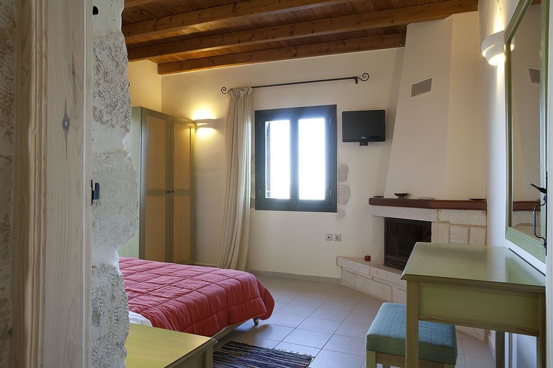 A bedroom with a bed, a window, a fireplace, and a small table.