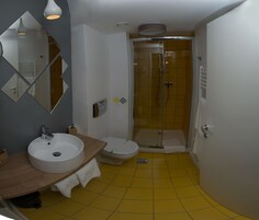 Un baño con lavamanos blanco, inodoro y cabina de ducha con paredes de vidrio.