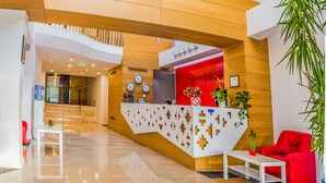 A modern hotel lobby with a reception desk, a staircase, and a red sofa. - Horeum Boutique Hotel (Sura Mare)