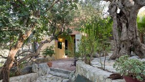 A courtyard with stone steps leading to a building, surrounded by trees and potted plants. - Kastellos Village - Agathes Houses (Apokoronas)
