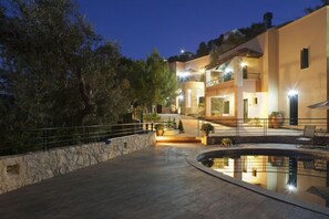Un bâtiment moderne à deux étages, doté d’une piscine, de murs en pierre et d’un éclairage extérieur.