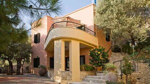 A Mediterranean-style building with a curved balcony, stone steps, and lush greenery. - Kastellos Village - Agathes Houses (Apokoronas)