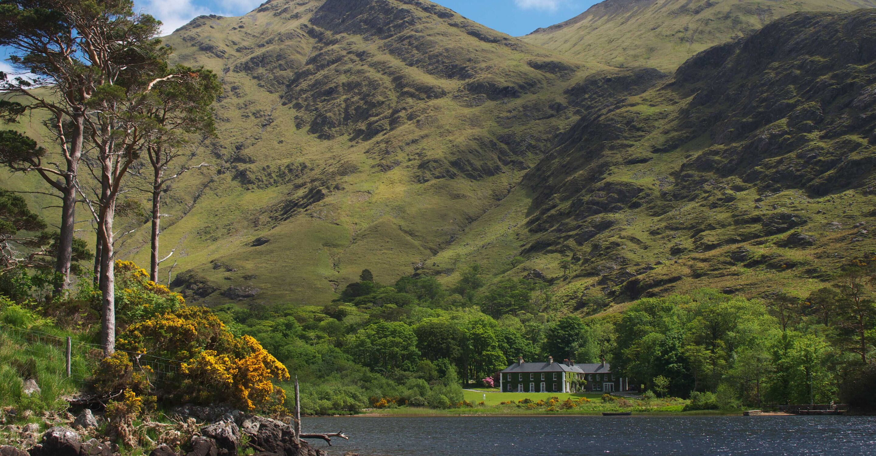 Una casa frente a un lago, con montañas al fondo.