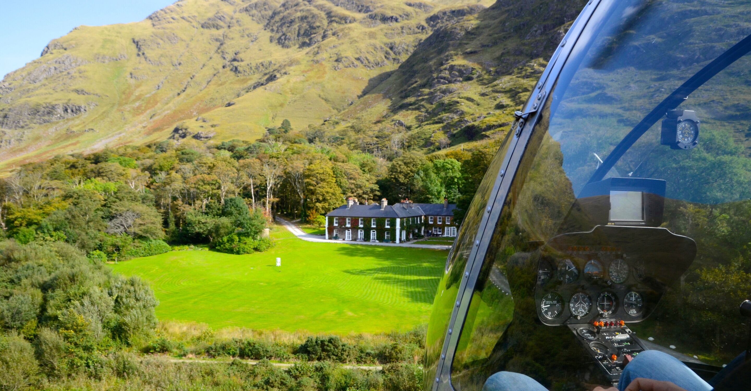 A helicopter view of a green field with a building in the distance.