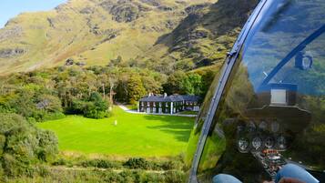 A helicopter view of a green field with a building in the distance.