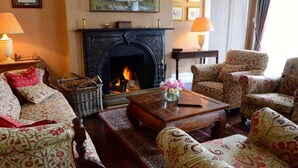 A traditional living room with a fireplace, patterned furniture, and a wooden coffee table. - Delphi Lodge & Estate (Leenane)