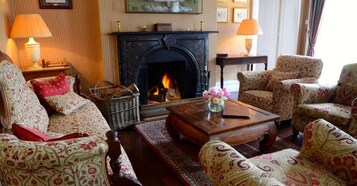 Un salón tradicional con chimenea, muebles estampados y una mesa de centro de madera.