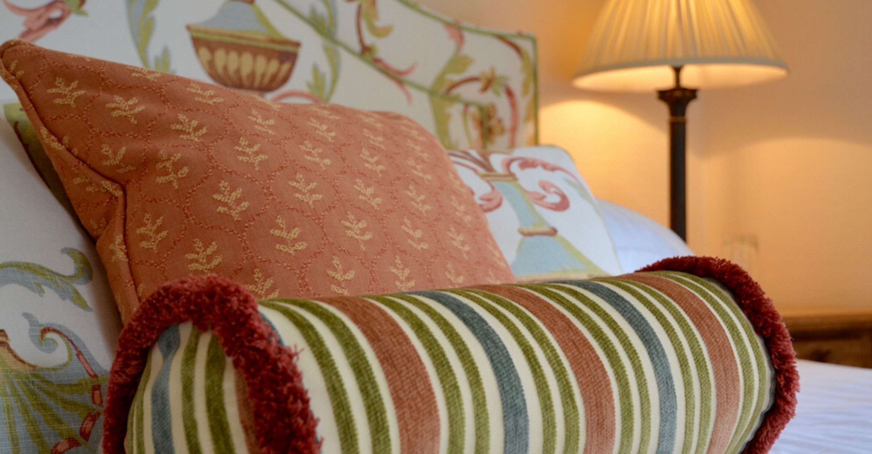 A bed with a striped pillow and a patterned pillow.