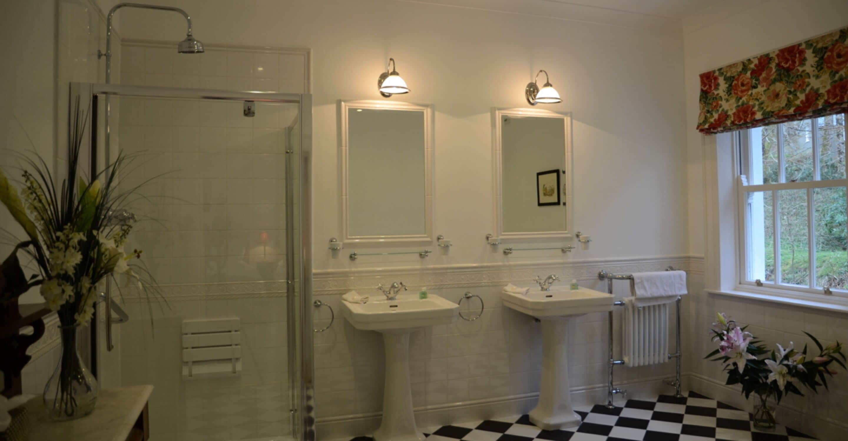 Un baño con ducha, dos lavamanos y una ventana.
