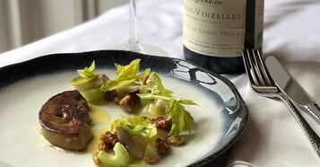 Un plato de comida con una botella de vino al fondo.