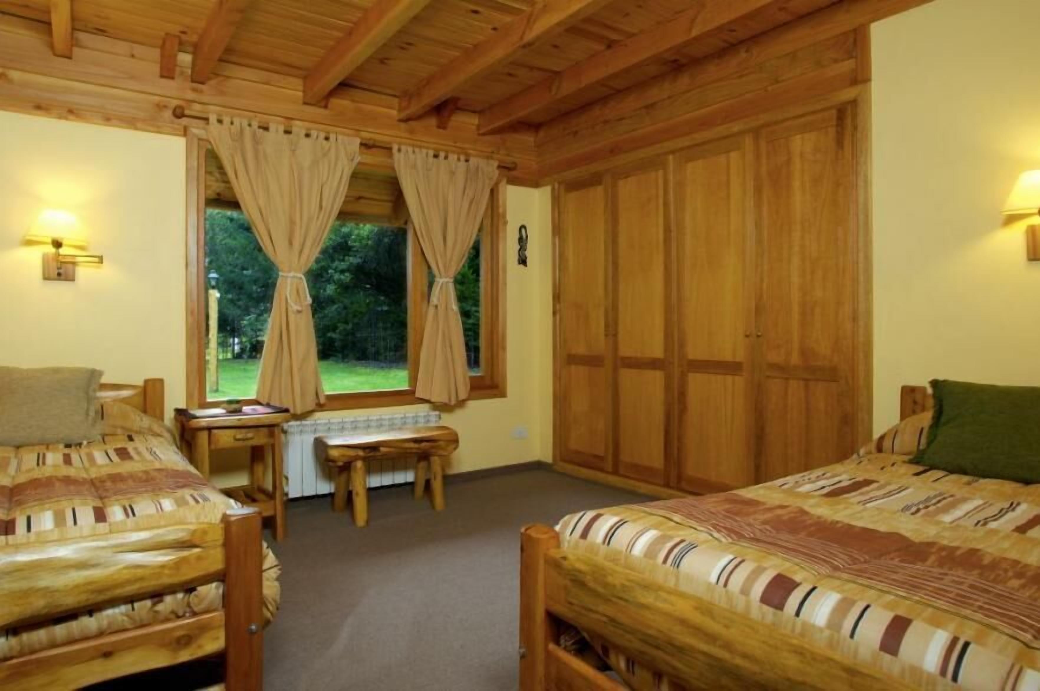 Een knus slaapkamer met twee houten bedden, een bureau en een grote kledingkast.