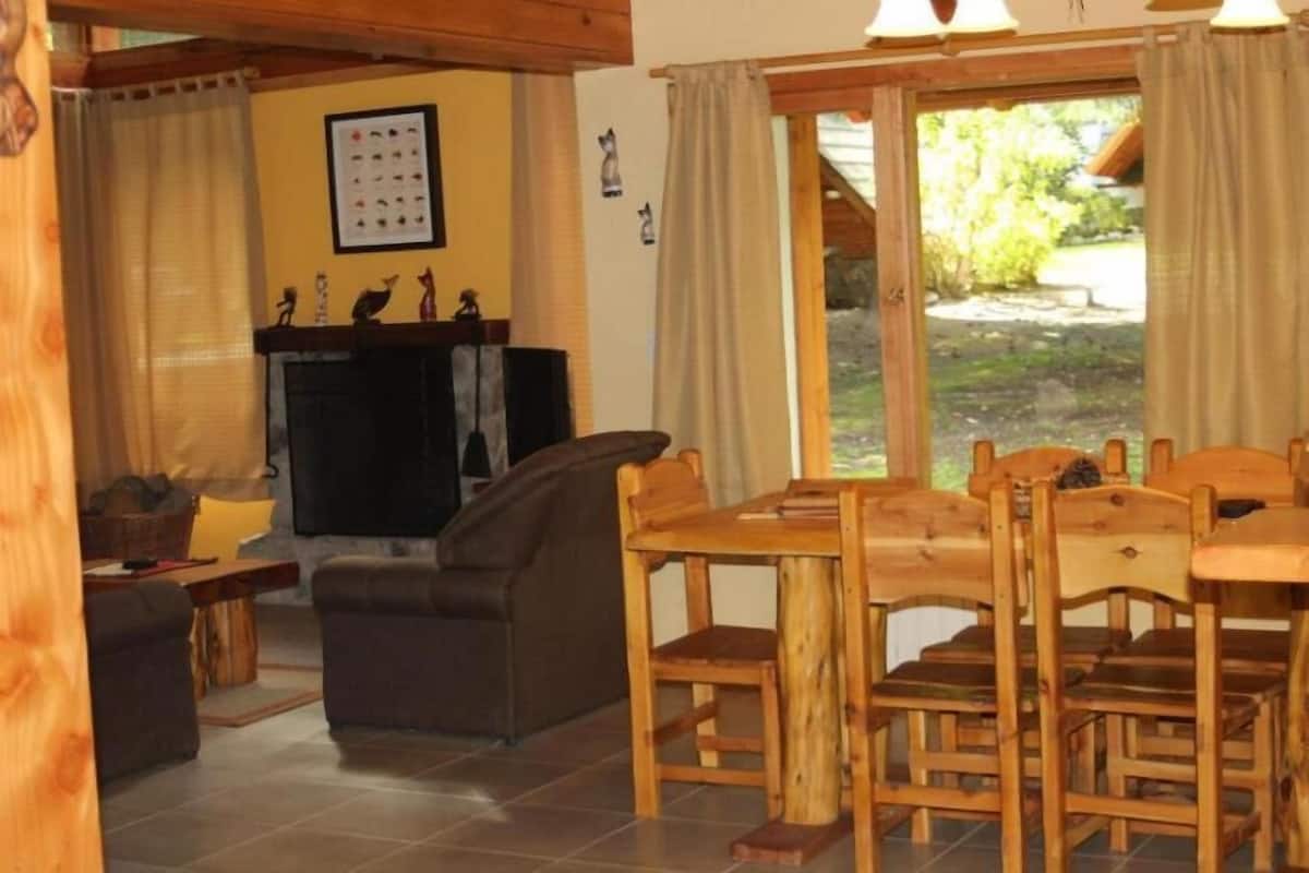 A cozy living room with a fireplace, wooden dining table, and comfortable seating.