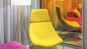 A room with a yellow armchair, a pink ottoman, and a floor lamp. - Ibis Styles Lviv Center (Lviv)