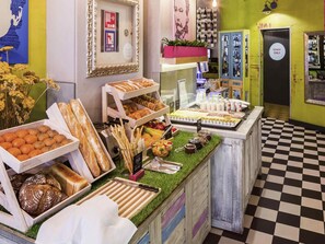Un bufé de desayuno con panes, bollería y frutas variadas.