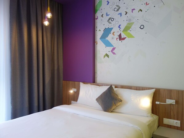 Una habitación de hotel con cama, cortinas, una pared con patrones geométricos y una lámpara.