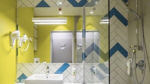 Un baño moderno con un espejo grande, un lavamanos y una ducha.