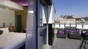 A modern hotel room with a balcony, a bed, a wardrobe, and a view of the cityscape. - Ibis Styles Lviv Center (Lviv)