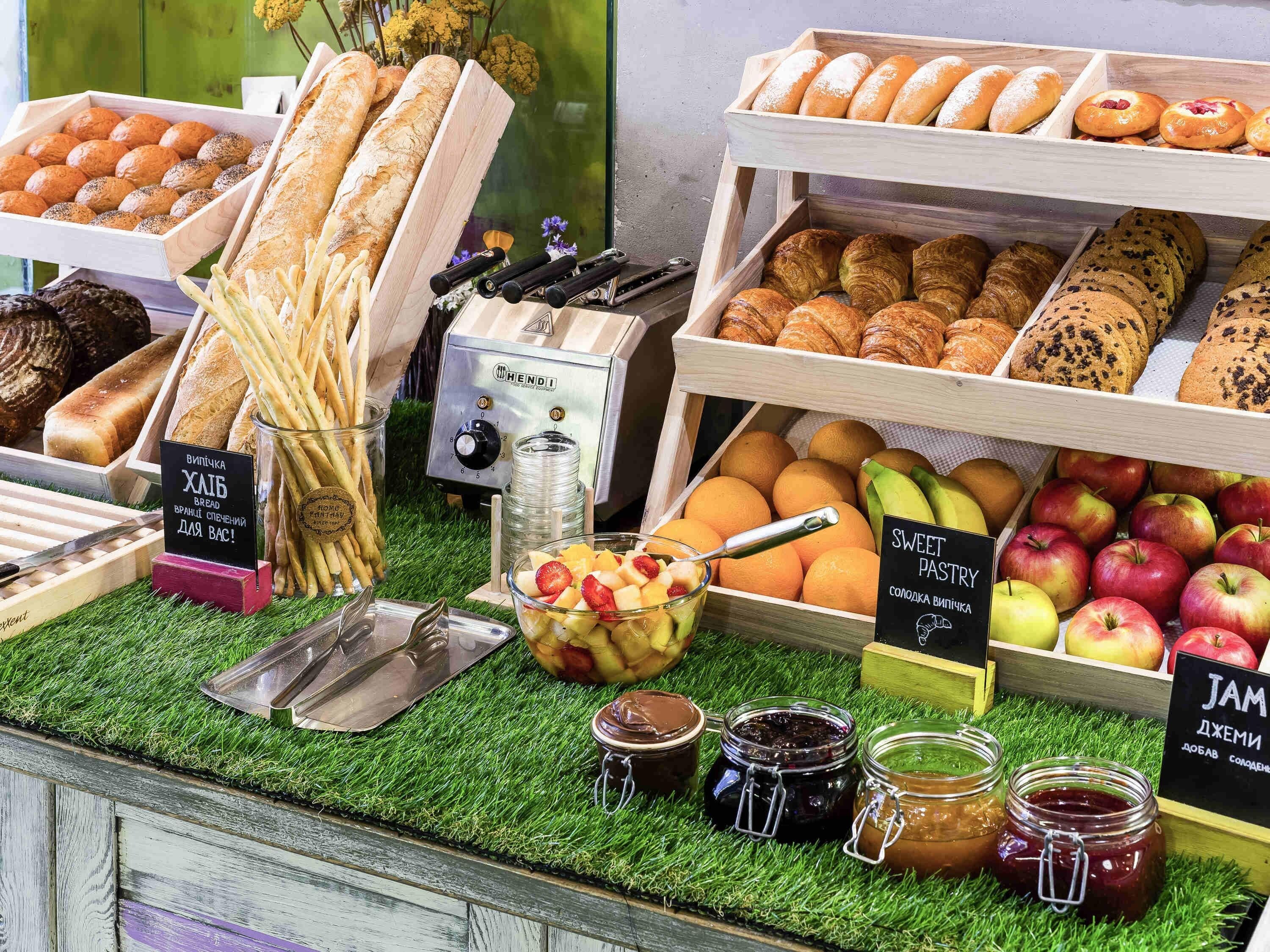 Una vitrina de panadería con panes, pasteles y frutas variadas.