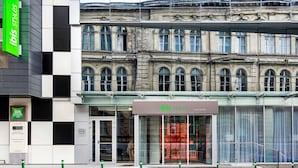 A hotel facade with a modern glass entrance and a classical building behind it. - Ibis Styles Lviv Center (Lviv)