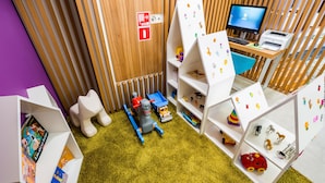A children's play area with a computer desk, shelves with toys, and a fire exit sign. - Ibis Styles Lviv Center (Lviv)