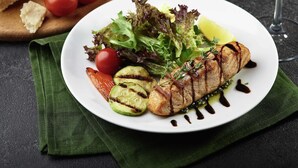 A plate of grilled fish with vegetables and a glass of white wine. - Ibis Styles Lviv Center (Lviv)