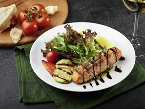 A plate of grilled fish with vegetables and a glass of white wine. - Ibis Styles Lviv Center (Lviv)
