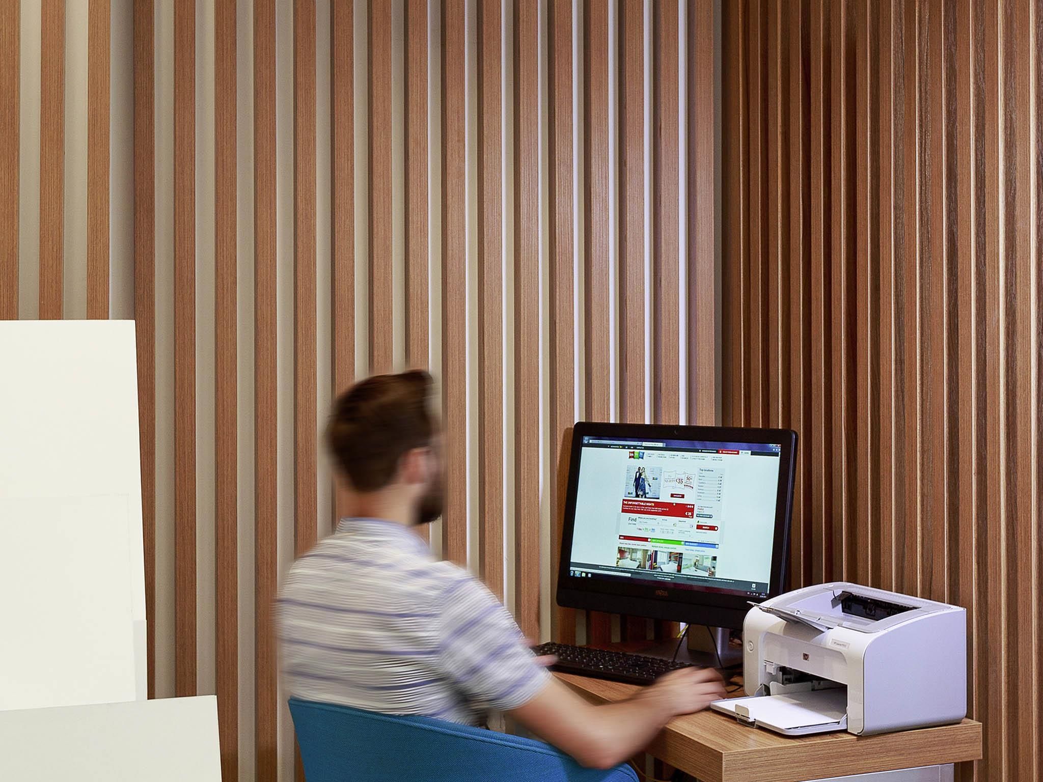 Una persona usando un ordenador de escritorio en una habitación con paneles de madera verticales.